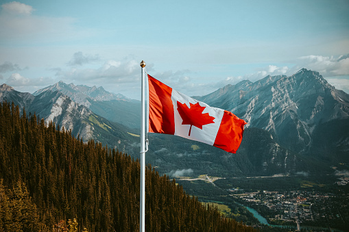 Canadian flag with mountain and small town views in summer