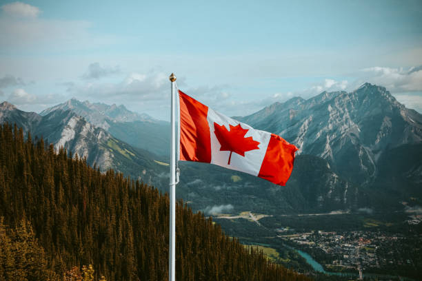 Canadian Flag in the Mountains Canadian flag with mountain and small town views in summer canadian culture stock pictures, royalty-free photos & images