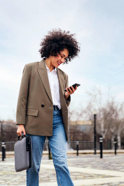 istock smiling young business woman walks using a phone 1413705177