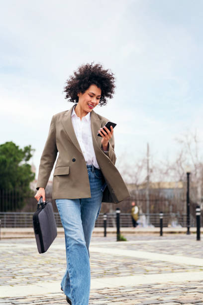 istock woman in a hurry walks fast using a smart phone 1413705178