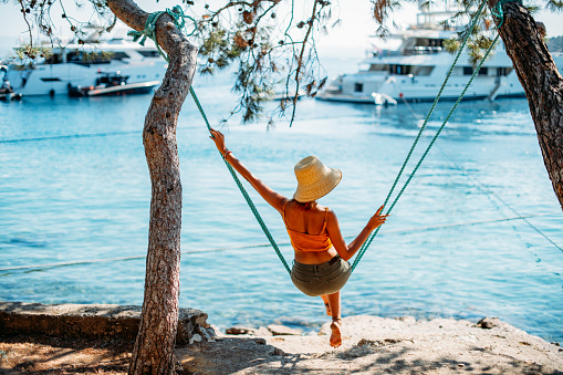 Young Woman Swinging on a Swing on the Beach