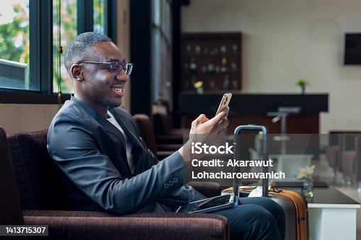 istock African American businessman is using mobile phone for video call while waiting in airline business departure lounge waiting for boarding the airplane 1413715307
