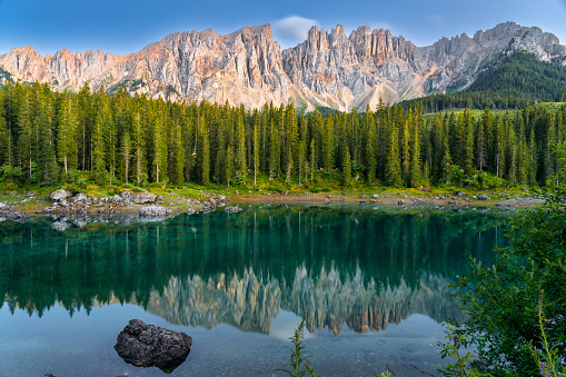 Italian alps. Silent morning on the lake of Carezza surrounded by pine forest and mountains.