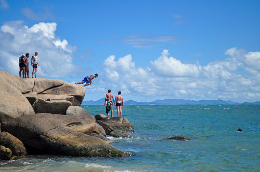 Bombinhas, Santa Catarina, Brazil - December 31, 2010 - Men jumping into the ocean at Tainha Beach. Summer adventure fun lifestyle