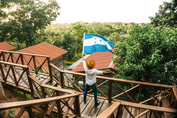 male tourist waving the flag of Honduras in front of some mountain cabins male tourist waving the flag of Honduras in front of some mountain cabins honduras stock pictures, royalty-free photos & images