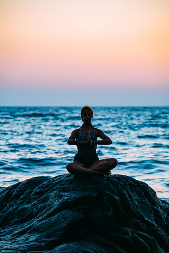 Young Woman Doing Yoga on the Beach at Sunset