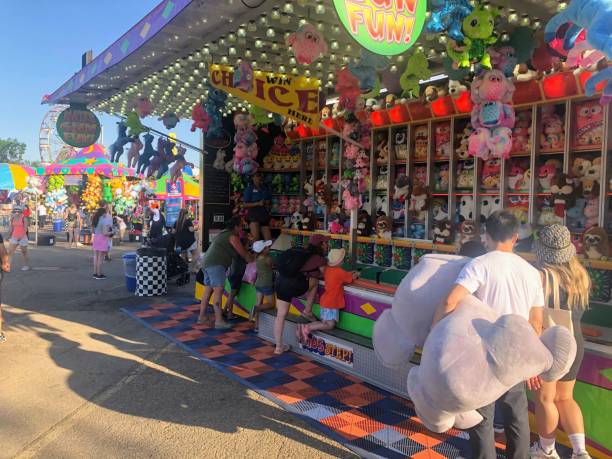 a group of people at a games booth trying to win a prize, at the summer exhibition k-days in edmonton, alberta, canada - rio carnival fotos imagens e fotografias de stock