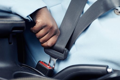 Close up of unrecognizable black woman fasting safety belt in car, copy space