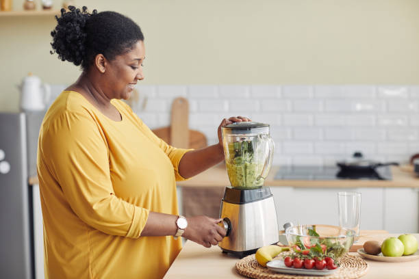 집에서 요리하는 흑인 여성 사이드 뷰 - electric juicer 뉴스 사진 이미지