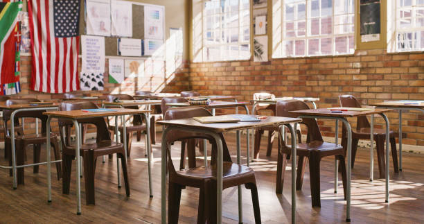 istock Empty classroom with wooden desks, table and chairs for a lesson inside an elementary, middle or high school. Education, learning and knowledge to study for teaching academic students, kids and youth 1413732603