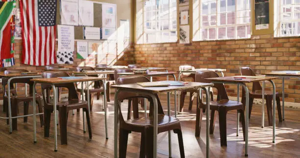 Photo of Empty classroom with wooden desks, table and chairs for a lesson inside an elementary, middle or high school. Education, learning and knowledge to study for teaching academic students, kids and youth