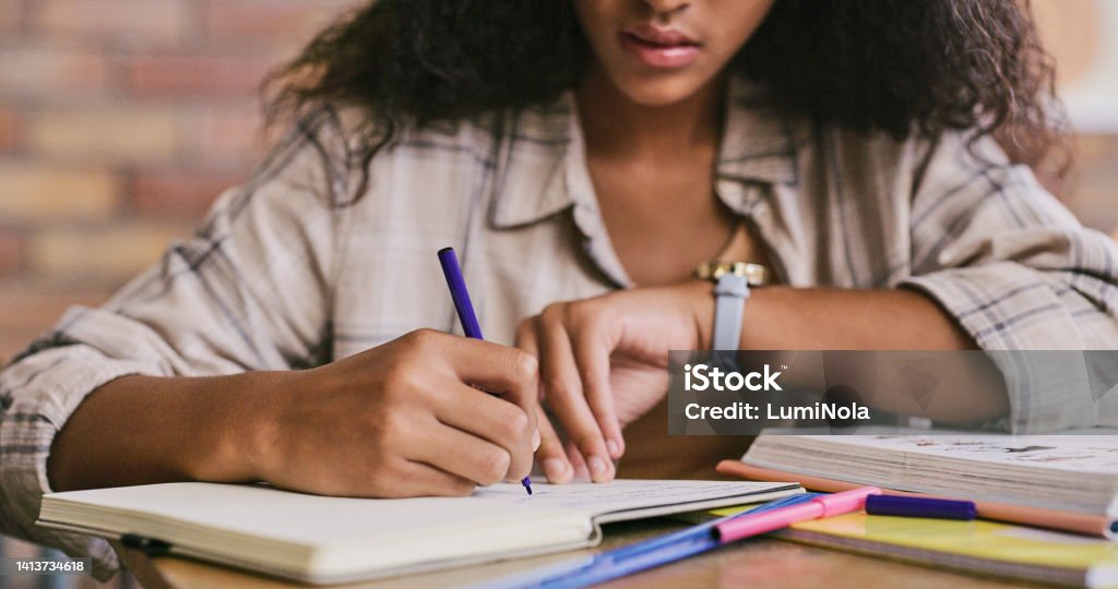 Clever, smart and intelligent female student writing in a book in a classroom in college. Closeup of African woman studying and drafting notes in a notebook inside a class at university Homework Stock Photo