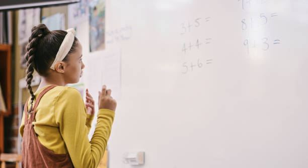 l’éducation, l’apprentissage et la réflexion des élèves tout en résolvant des équations mathématiques sur tableau blanc et en comptant sur les doigts. petite écolière intelligente faisant une somme additionnelle tout en calculant la réponse o - blackboard child thinking little girls photos et images de collection