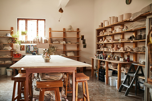 Studio, art store and pottery workshop with wooden table, chairs and furniture for hobby lesson class. Storage room with tools, pots and vases for a clay or ceramic mud to make, shape or design craft