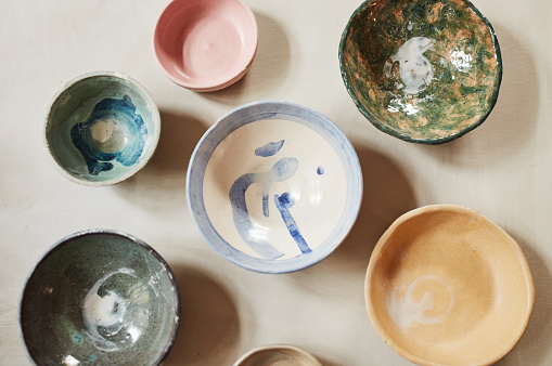 Traditional Japanese bowls from an overhead view on a table with a unique design and texture. Many antique, vintage and old dishes of different round sizes in a kitchen counter