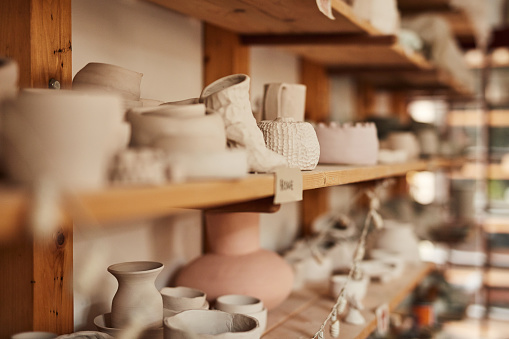 Clay cups, pots and pottery bowls with creative and traditional art designs in an entertainment and artistic workshop. Decoration arts and craft manufacturing store to make handmade objects a hobby