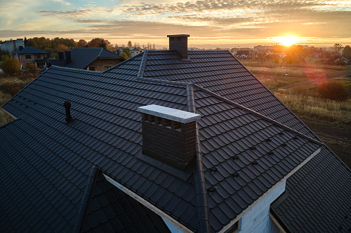 Aerial view in worker hands installing bitumen roof shingles with air hammer and nail