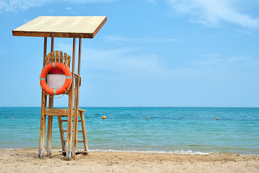 Emplty wooden lifeguard station on sandy beach on ocean shore in summer.