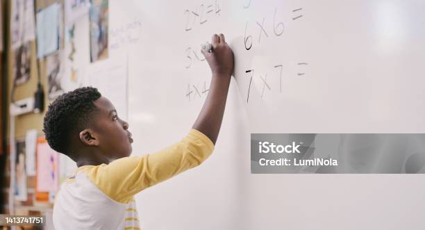 Education Classroom And Learning While Black Student Solve A Maths Equation And Write Answers On The Whiteboard Smart Little School Boy Doing Multiply Sum And Calculating A Solution In Class Stock Photo - Download Image Now