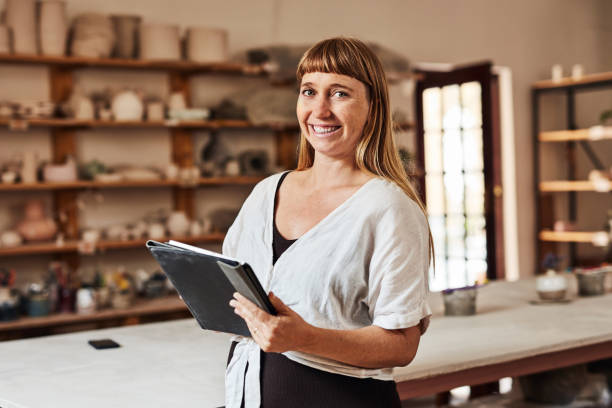 artista della ceramica, creativo e designer con tablet tenendo e leggendo lezioni o lezioni in studio d'arte. ritratto di vasaio sorridente, felice o artistico nel laboratorio artigianale fatto a mano o nel negozio di prodotti - potter small business pottery happiness foto e immagini stock