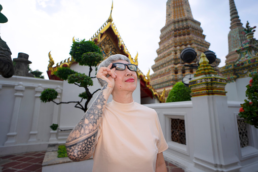 Senior woman is solo traveler. She is enjoy to explore her world. Asia culture. Bangkok Thailand. Wat pho is public temple for praying Buddha.