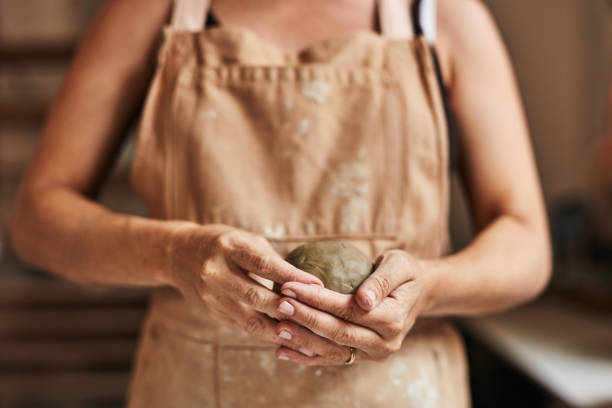 워크샵 아트 스튜디오에서 점토 공이나 덩어리를 들고있는 도자기 전문가의 손. 창조적 인 포터 장인 조각, 성형 및 성형 원료를 사용하여 손가락으로 디자인 제품을 만듭니다. - shaping clay 뉴스 사진 이미지