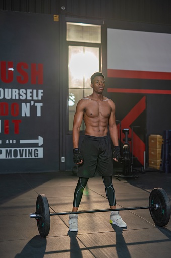 Photo of a handsome and muscular black male doing weight lifting in a gym