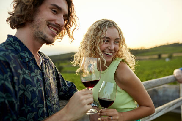 pareja joven sonriente disfrutando de una cata de vinos al aire libre - winemaking vintner winery people fotografías e imágenes de stock