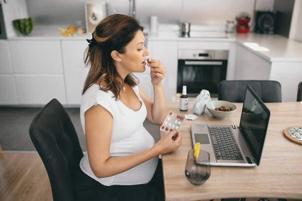 Pregnant woman taking pill at home. stock photo