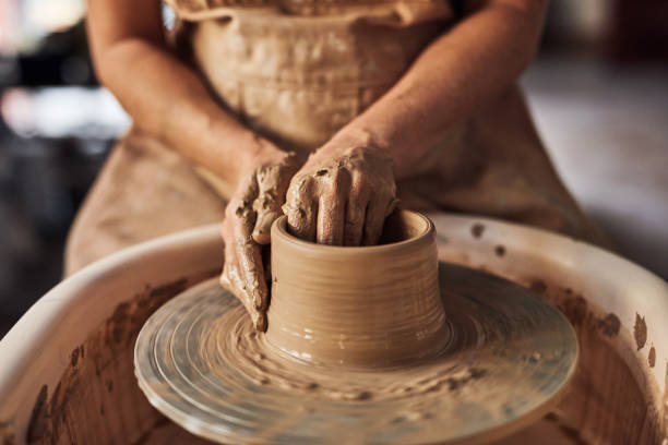 istock Creative female working on a pottery wheel making art crafts relaxing in her home workshop enjoying her hobby. Professional potter shaping wet clay to form artistic decorative products in a studio 1413753008