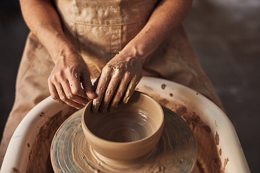 Pottery, design and art worker molding clay pot in a ceramic workshop studio. Closeup of a female potter hands working and busy creating, making or designing a creative handmade bowl shape indoors