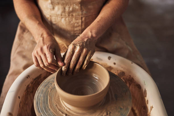 cerâmica, design e arte de moldagem de pote de argila em um estúdio de oficina de cerâmica. close-up de uma mão de oleiro feminina trabalhando e ocupado criando, fazendo ou projetando uma forma criativa de tigela artesanal dentro de casa - potter human hand craftsperson molding - fotografias e filmes do acervo