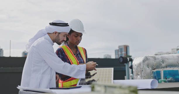 arab engineer and construction workers are installing solar panels on the building for use in energy saving and environmentally friendly. solar energy investment stock photo