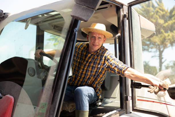 istock Focused busy farmer driving tractor working on farm 1413754456