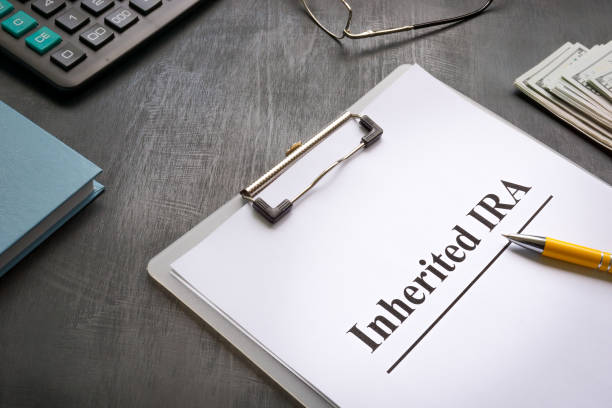 istock Inherited IRA papers next to a calculator and notepad. 1413754705
