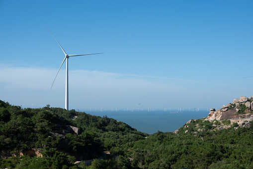 Mountain peaks and wind turbines by the sea