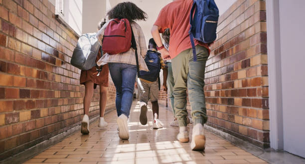 istock School students running or walking to an education class for learning from behind. Low angle rear view group of young little children together leaving or going to play on their break 1413756538