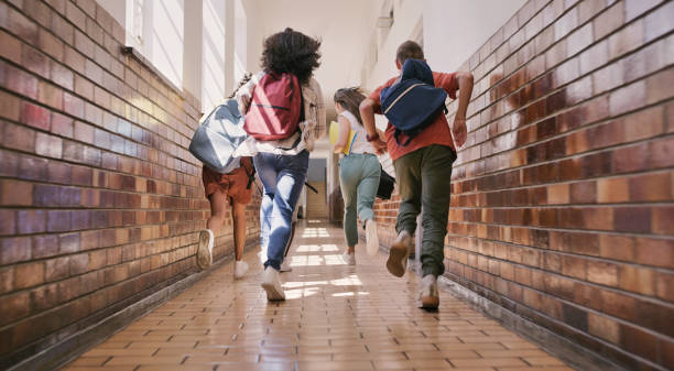 Fun, happy and excited school students running, racing and rushing down a school hallway to break or recess. Rearview of a group of diverse and playful children sprinting to play with their friends Fun, happy and excited school students running, racing and rushing down a school hallway to break or recess. Rearview of a group of diverse and playful children sprinting to play with their friends primary school assembly stock pictures, royalty-free photos & images