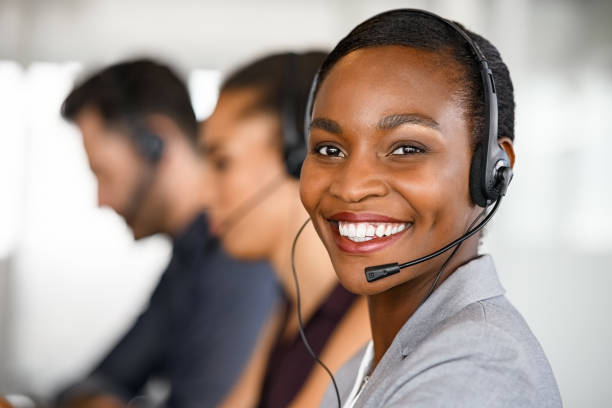 mulher de atendimento ao cliente madura negra de plantão com grande sorriso - customer service representative service african descent receptionist - fotografias e filmes do acervo