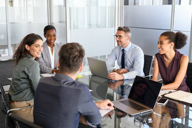 Group of business people in meeting working together Group of business people have a discussion in conference room. Formal business team brainstorming over new project. Mature businessman and businesswoman talking and working  while sitting in modern conference room with business partners. staff meeting stock pictures, royalty-free photos & images