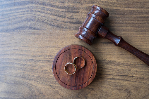 Wooden gavel and wedding rings on wooden background. Directly above. Great use for family law and divorce concepts.
