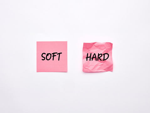 The words soft and hard on pink sheets of note paper. Soft skills and hard skills concept