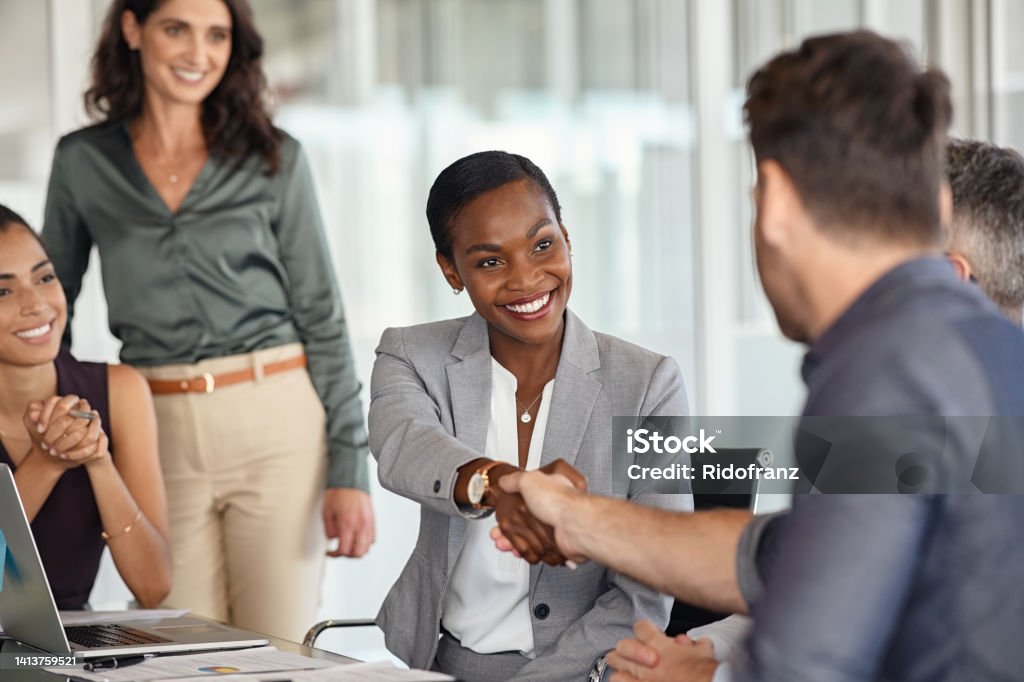 Donna d'affari nera matura che stringe la mano al nuovo partner commerciale - Foto stock royalty-free di Affari Donna d'affari nera matura che stringe la mano al nuovo partner commerciale - Foto stock royalty-free di Affari