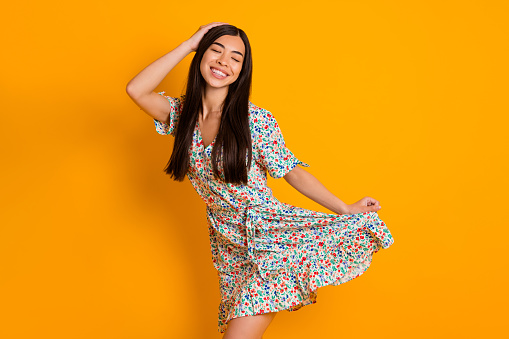 Portrait of cheerful pretty person closed eyes arm hold touch long dress isolated on yellow color background.