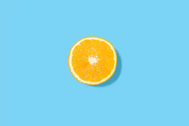 Bright orange slice on a blue background - minimalist summer composition