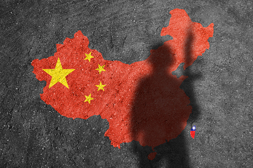 China and Taiwan flag map painted on a concrete wall with soldier shadow