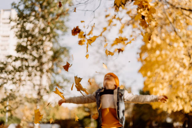 istock Kid having fun in autumn park with fallen leaves, throwing up leaf. Child boy outdoors playing with maple leaves. 1413761476
