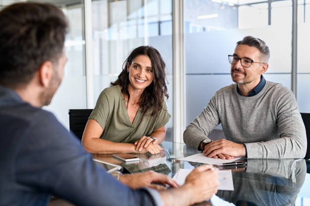 Mature couple meeting financial advisor for investment Smiling mature couple meeting with bank manager for investment. Beautiful mid adult woman with husband listening to businessman during meeting in conference room in modern office. Happy middle aged couple meeting loan advisor to buy a new home. insurance agent stock pictures, royalty-free photos & images