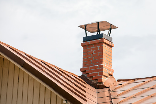 Red brick chimney with a metal roof.