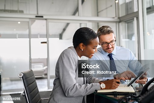 istock Business partners working on digital tablet in modern office 1413764598